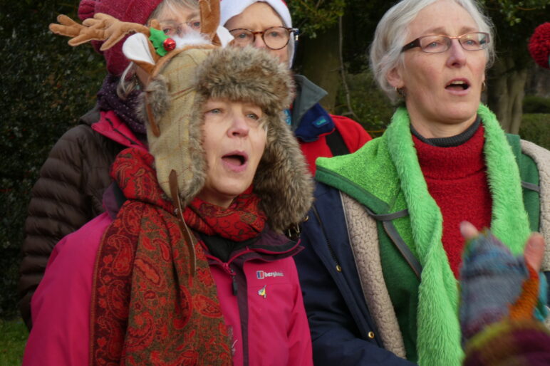 Four singers as part of a choir wearing red and green Xmas outfits