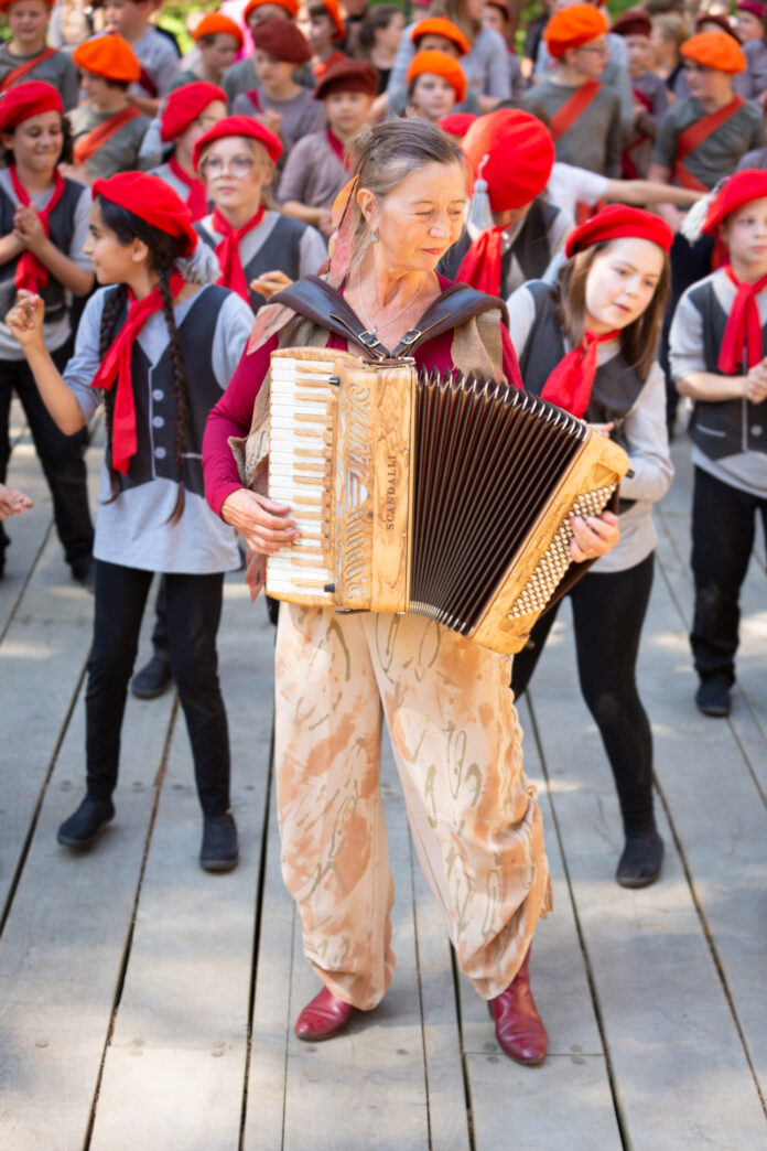 The photo stems from a recent intergenerational out reach project, leading to a musical theatre show, involving members of the community as well as a professional cast. Martina was leading people with music and song. She wrote a number of songs for this project and also performed in the show. Her perfect scenario!